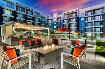 a seating area with a firepit and chairs in front of an apartment building